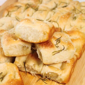 Easy focaccia bread from frozen rolls piled on wooden board.
