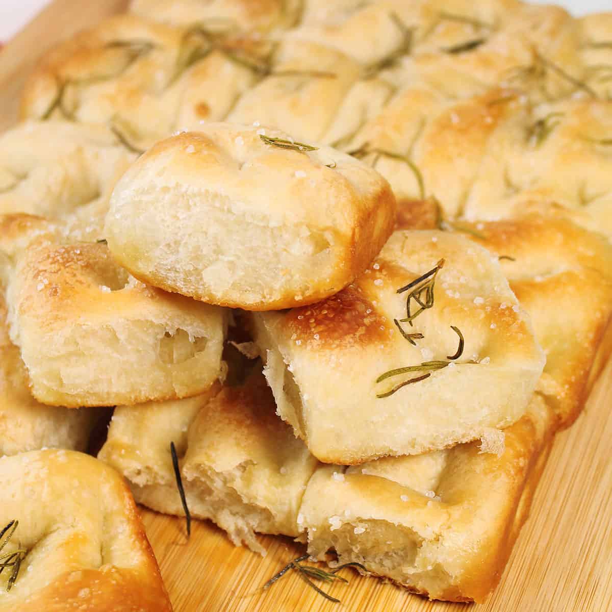 Easy focaccia bread from frozen rolls piled on wooden board.