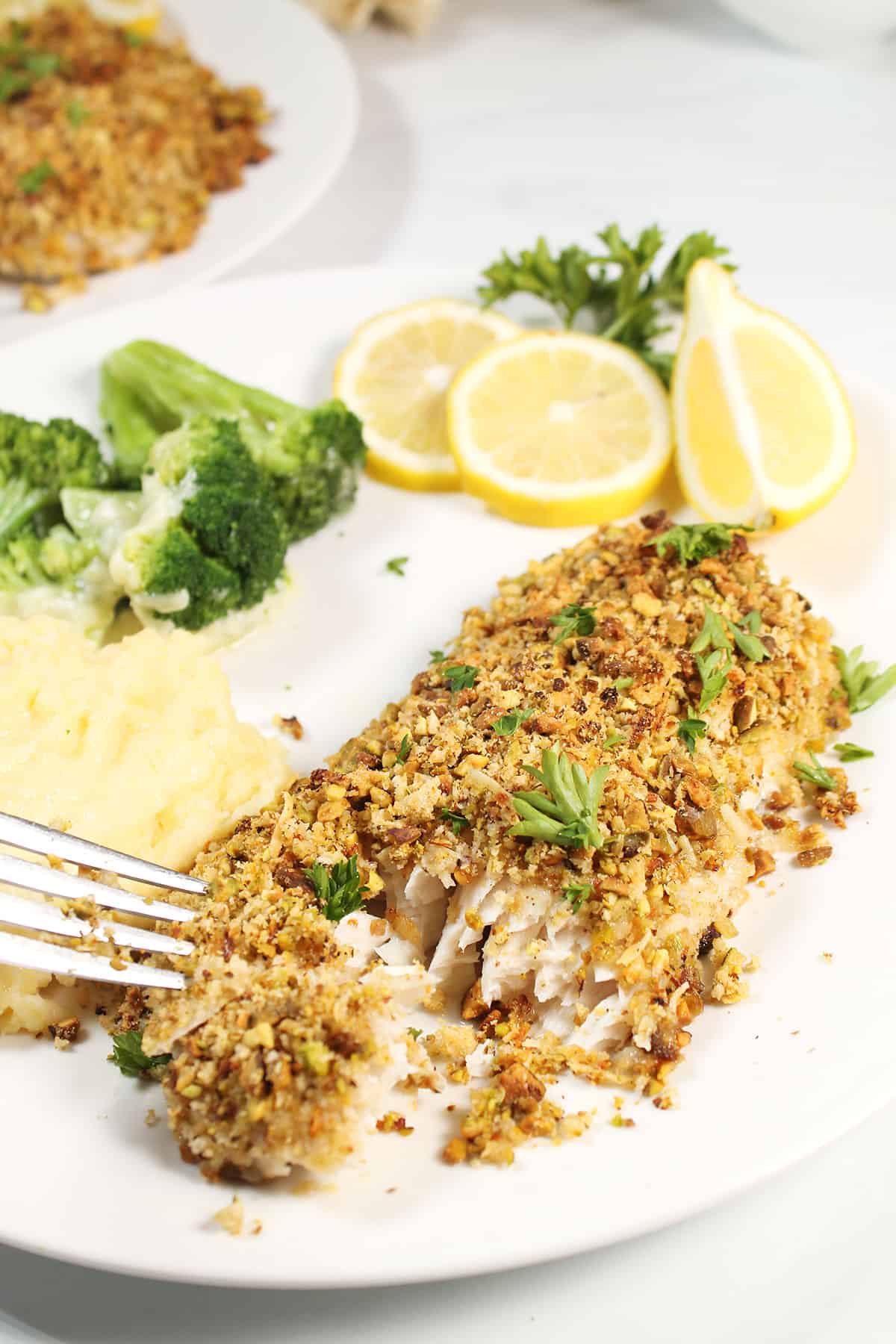 Plated Pistachio Crusted Mahi with fork showing flakiness.