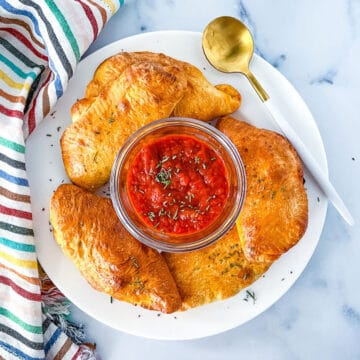 Mini calzones on plate with dipping sauce.