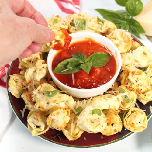 Air Fryer Tortellini on platter dipping into marinara.