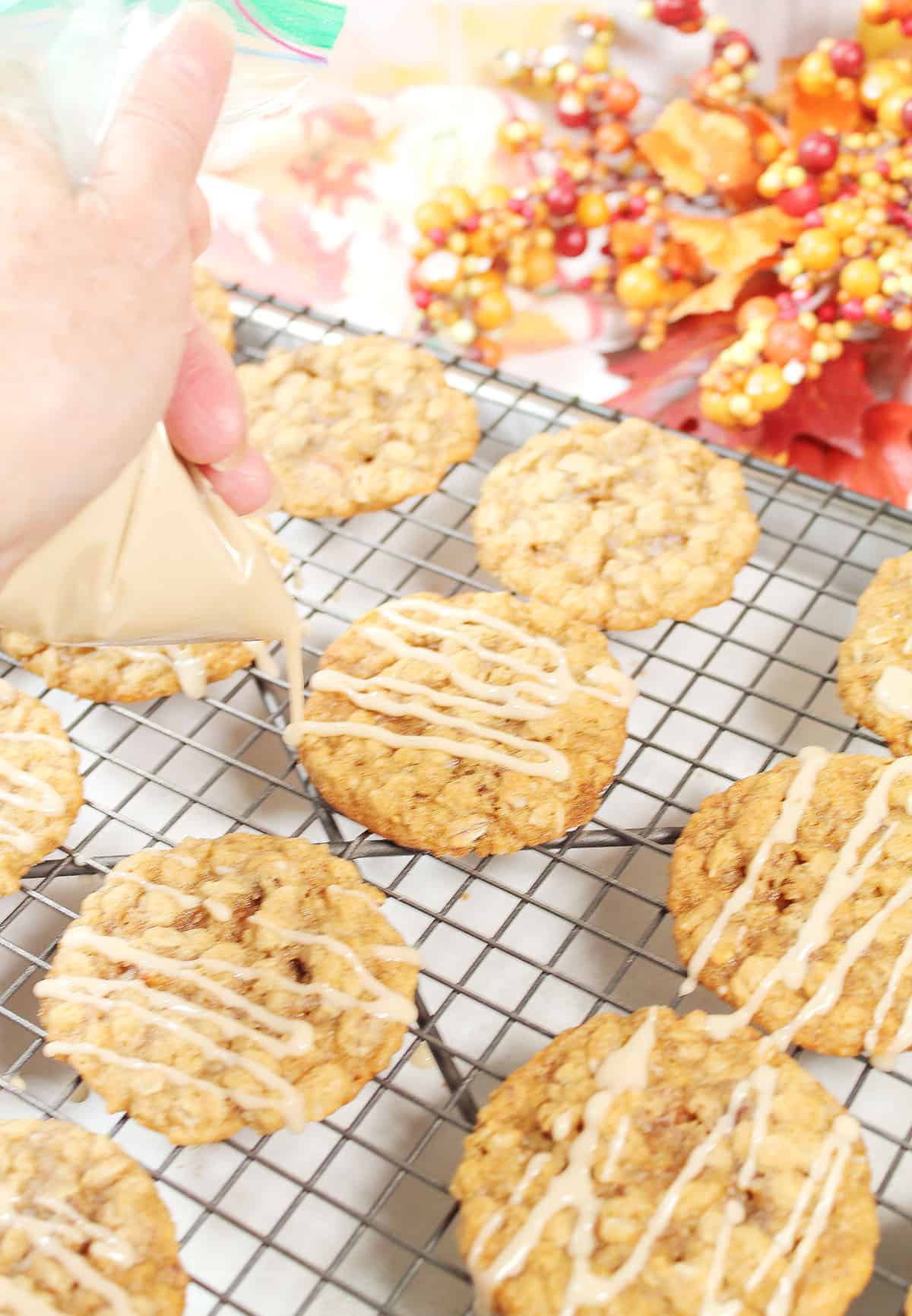 Drizzling maple frosting over cooled cookies.
