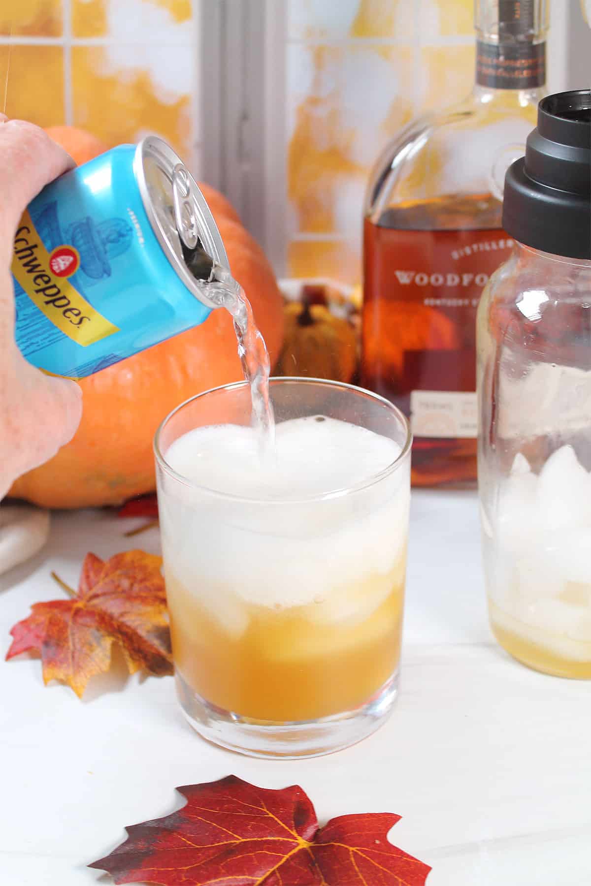 Pouring club soda into bourbon drink.