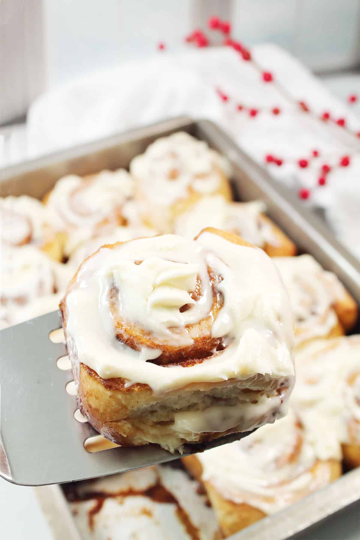 Lifting a warm Gingerbread Cinnamon Roll out of pan.