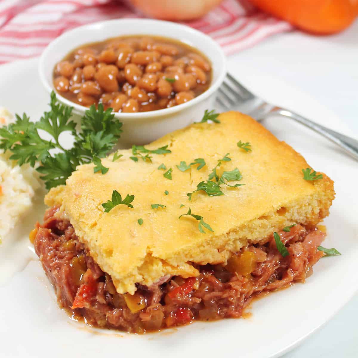 Closeup of pulled pork casserole with cornbread topping on plate.
