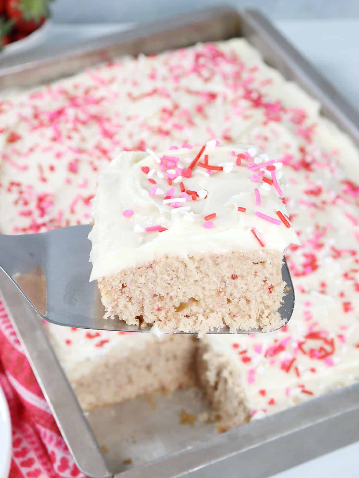 Lifting slice of Pink Velvet Cake out of baking pan.