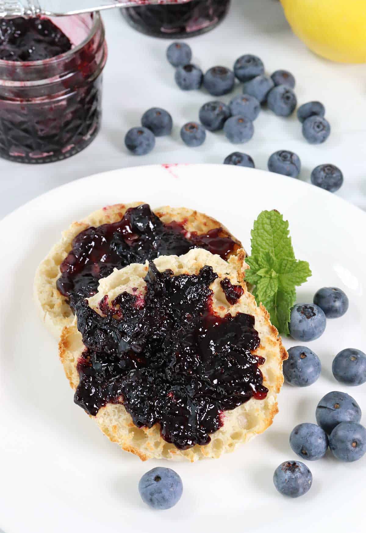 Blueberry Jam, no pectin, on a muffin with jam jar in back.