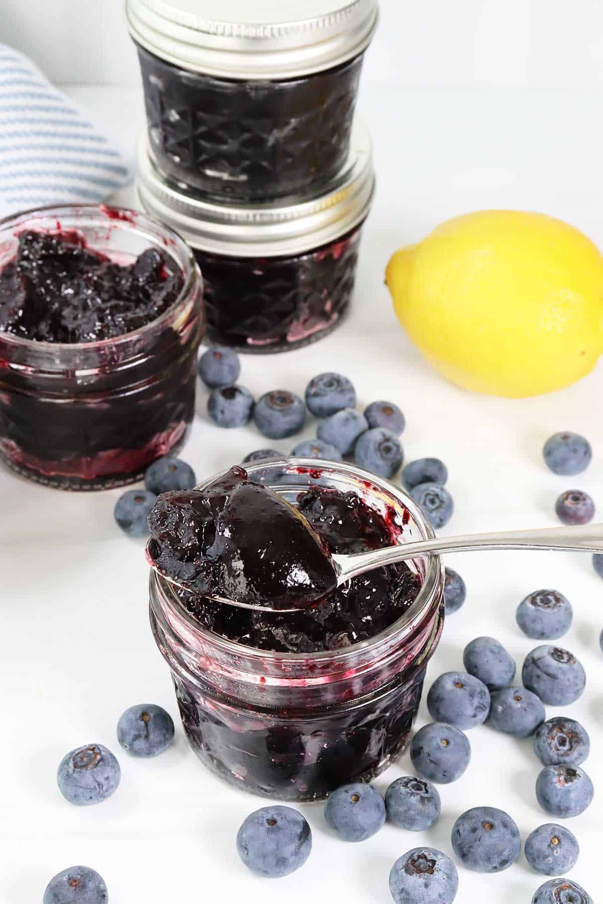 Blueberry jam on spoon over jar.