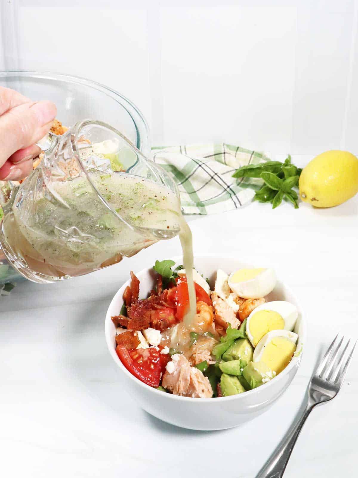 Pouring dressing over a serving of cobb salad.